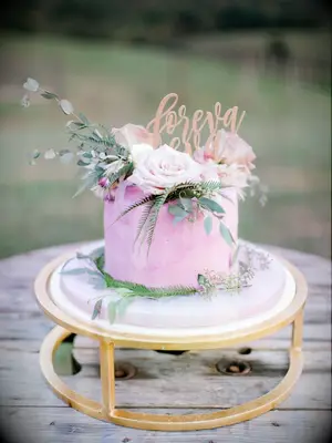 purple one tier wedding cake on gold stand with roses and greenery