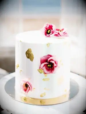 small one tier wedding cake with pink flowers and gold leaf