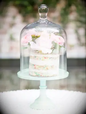 milk bar wedding cake displayed in glass cloche jar with fresh flowers on top