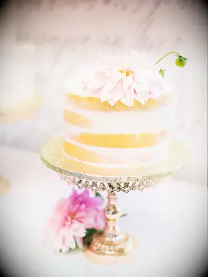one tier wedding cake with semi-naked frosting and pink cafe au lait dahlia on gold cake stand