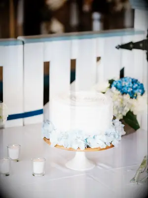 classic one tier wedding cake with white buttercream frosting and blue hydrangeas