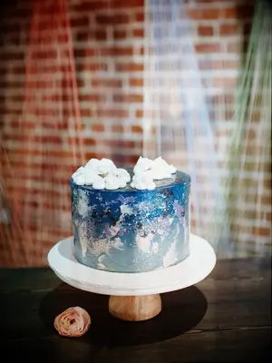 celestial one tier wedding cake with blue and purple design and white meringues as clouds on top