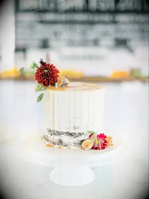 fall one tier wedding cake with caramel drip icing and burgundy flowers