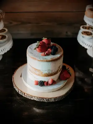 small one tier wedding cake with strawberries, raspberries blueberries and powdered sugar