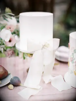 white fondant one tier wedding cake with ivory satin bow at the base