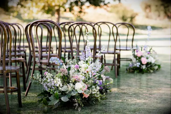 outdoor wedding ceremony aisle marker with blue and purple delphinium, pink peonies and greenery