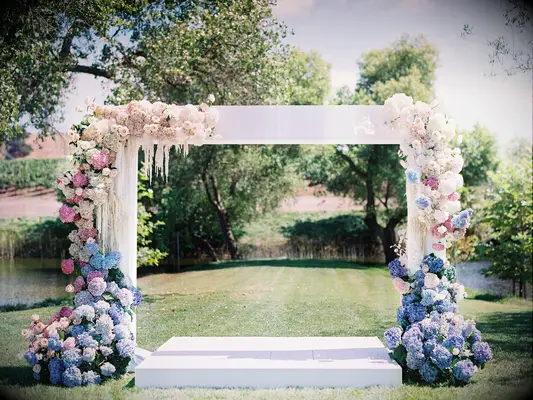 pastel wedding ceremony arch with blue, pink and white hydrangeas, pink roses and white amaranthus against a white square frame