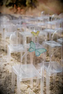 clear acrylic ghost chairs at outdoor wedding ceremony decorated with light green butterfly
