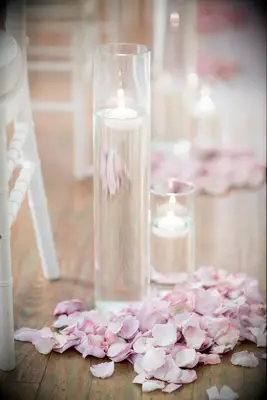 wedding ceremony aisle marker with pastel pink rose petals and floating candles in glass vases