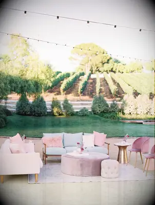 outdoor wedding reception with lounge area featuring pink, blue and lilac sofas and chairs