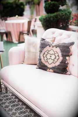 closeup of wedding lounge area with blush pink sofa and pink boho patterned throw pillow