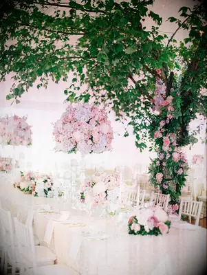 tall pastel wedding centerpiece with pink roses and blue hydrangeas displayed on glass stand