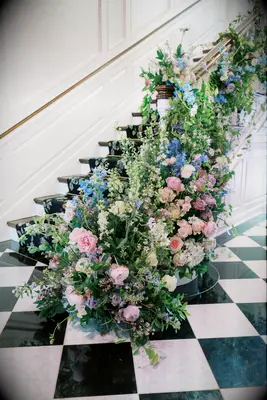 staircase bannister at historic wedding venue decorated with blue delphinium, pink roses and greenery vines