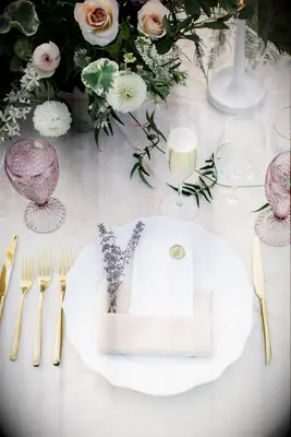 classic wedding place setting with pastel purple glassware, gold flatware, blush pink napkin and fresh lavender sprigs
