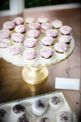 macarons dipped with light purple frosting and almonds arranged on a gold tray