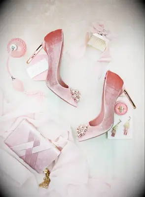 styled wedding flat lay with blush velvet stiletto heels, satin box clutch, chloe perfume bottle, and pink tassel earrings
