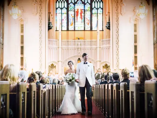 Bride and groom walk down the aisle at a church.