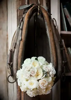 Western horse saddle holds a bouquet of beautiful white roses. 