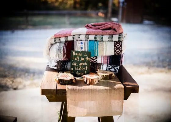 Cozy and stylish blankets stacked and ready to be used by guests during the wedding ceremony. 