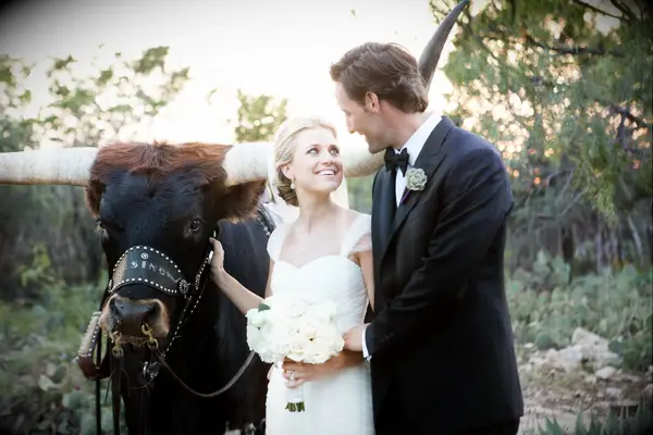 Newlyweds pose with a longhorn at their ranch-style wedding. 