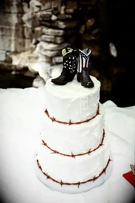 White wedding cake topped with rustic cowboy boot topper. 