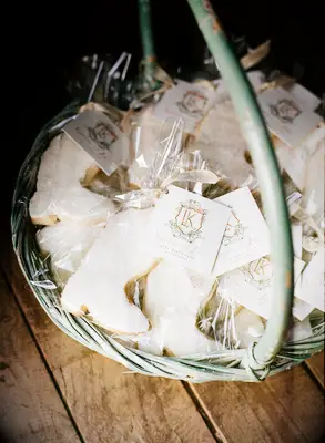 Cowboy-boot shaped cookies wrapped in cellophane sit in a pale green basket to be given to guests as party favors. 