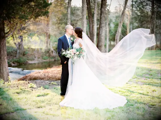 Film-style wedding photo of bride and groom kissing outside