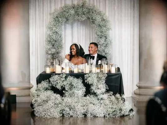 Traditional wedding image of Couple Sitting at Sweetheart Table Decorated With Baby