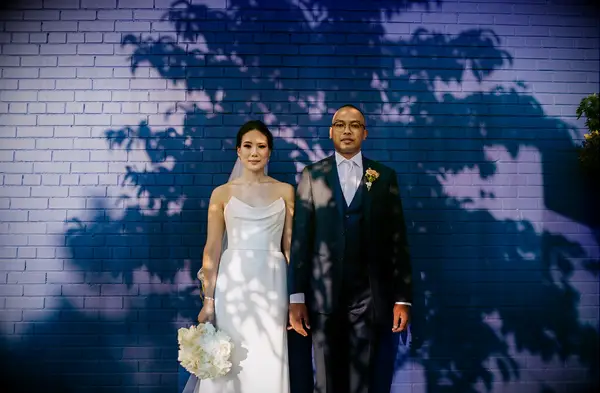 Lifestyle wedding image of Bride and Groom standing in front of blue wall