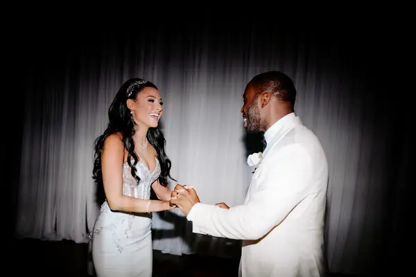 Flash photography-style image of bride and groom holding hands and laughing