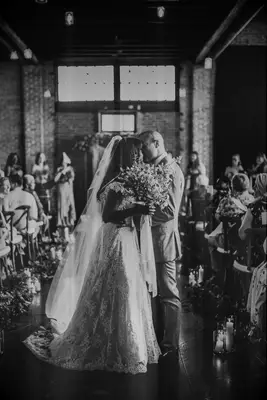 Vintage-style image of bride and groom kissing at ceremony