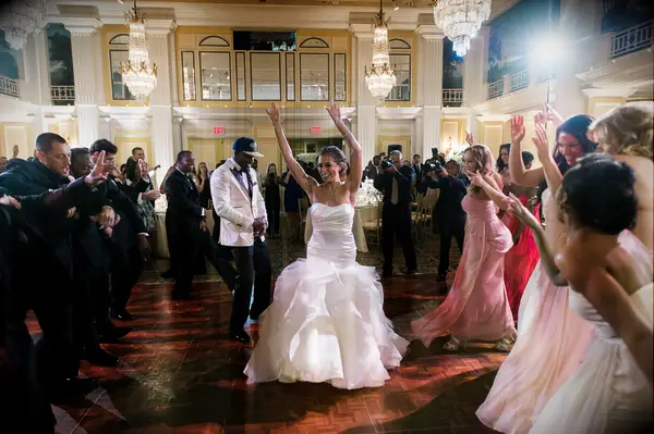 bride and groom making their entrance to the ballroom dance floor while guests cheer & clap