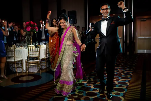 bride wearing a pink and gold lehenga holds groom