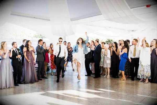 bride and groom wearing matching sunglasses dance their way into wedding reception