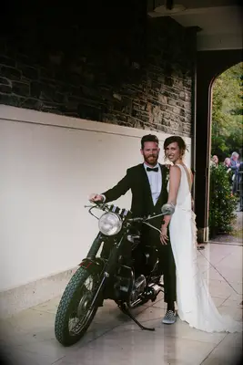 bride and groom pose with a vintage 1969 motorcycle at their wedding venue