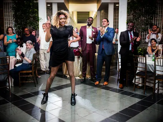 Grooms with guests watching drag performance at wedding reception