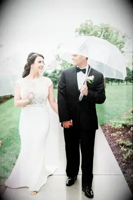 Bride and Groom Under Clear Umbrellas at Rainy Wedding