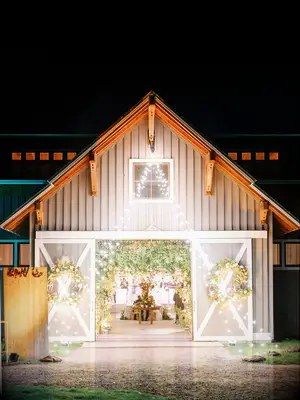 exterior of barn wedding venue decorated with string lights from the roof to the ground