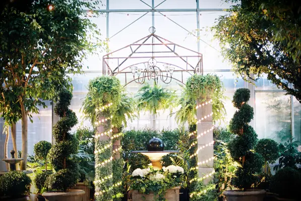 topiaries and stone columns at greenhouse wedding venue decorated with LED tube lights