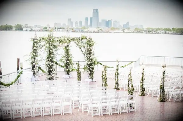 Greenery chuppah at waterfront patio with skyline views in the background. 