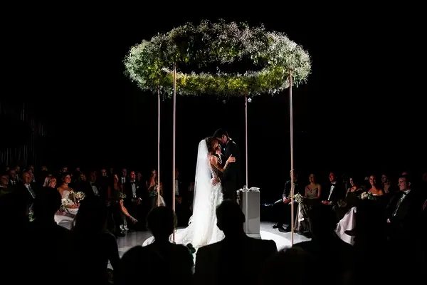 Couple standing under circular chuppah.