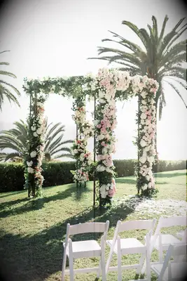 Chuppah covered in pink roses at oceanfront wedding.