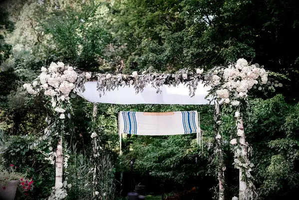 Floral chuppah with tallit suspended from the top.