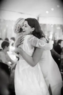 Candid blurry wedding photo of bride hugging guest