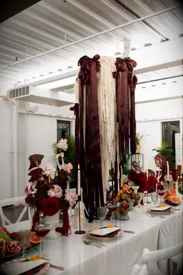 tall wedding centerpiece with white amaranthus, burgundy satin bows and ribbons with white taper candles