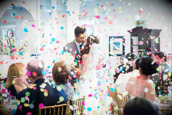 Bride and groom standing in a colorful confetti shower. 