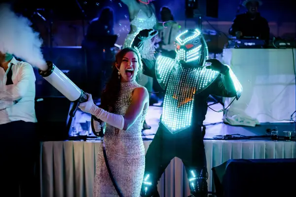 Groom dressed in a LED robot suit and bride using a fog smoke machine.