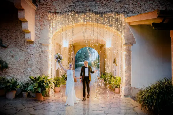 Bride and groom entering reception through string light curtain.