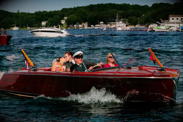 Bride and groom riding in a red boat for their reception entrance.
