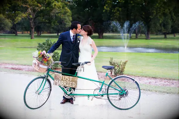 Bride and groom standing next to a tandem bike.
